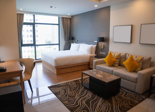 Modern studio apartment design with bedroom and living space. Hotel room panoramic window, king sized bed, couch and coffee table. City flat concept